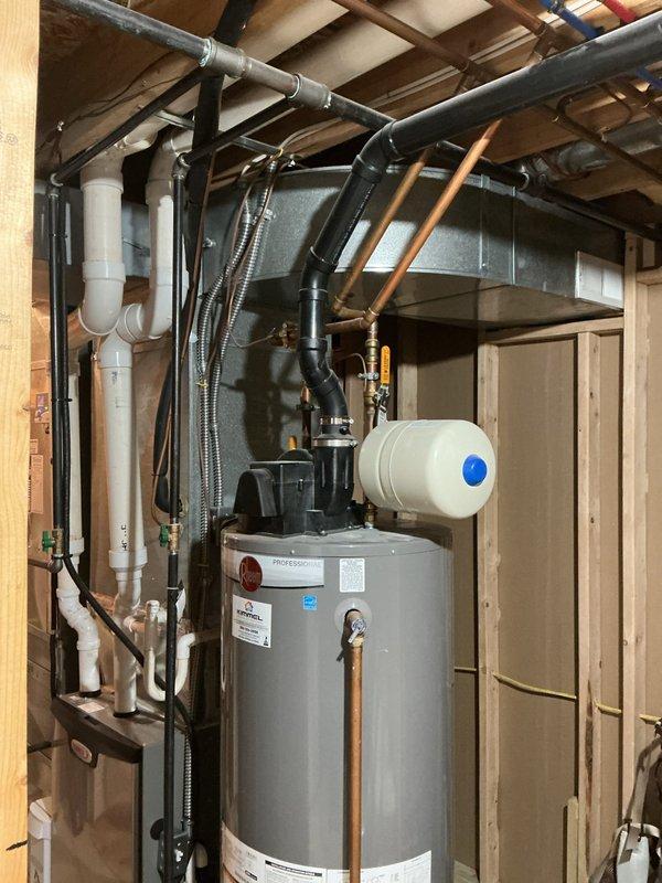 Responded to service call to provide estimate for natural gas water heater replacement. Inspected existing unit in basement utility area, which included a cylindrical tank with expansion tank mounted on top. Documented current plumbing configuration including copper supply lines, PVC/ABS drain pipes, and associated valves and fittings to prepare accurate replacement quote.