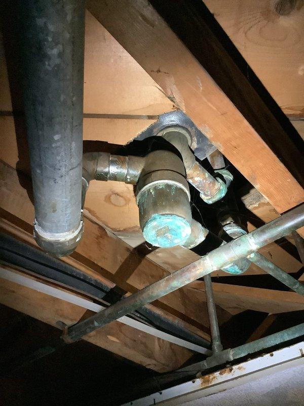 Responded to service call for leaky shower drainpipe in 70-year-old home. Upon inspection, discovered significant oxidation and corrosion on copper drain assembly beneath tub. Replaced damaged pipe sections, sealed all connection points, and verified proper drainage with pressure test. No further leakage observed after repair.