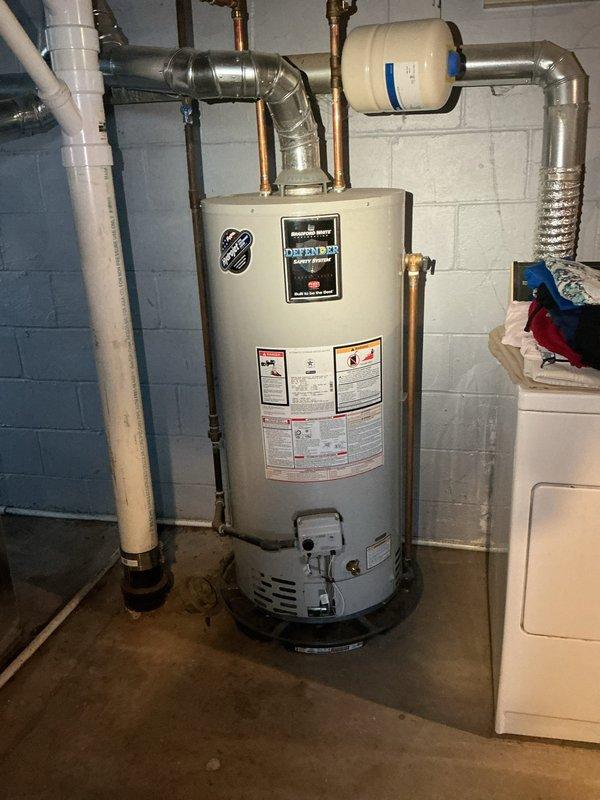 Performed flush and fill service on Bradford White "Defender" tanked water heater as requested by HVAC department. Inspected complete system including expansion tank, copper supply lines, and ventilation components. System is properly installed against concrete block wall with all connections secure and functional.