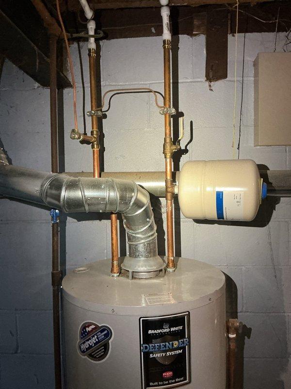 Performed flush and fill service on Bradford White "Defender" tanked water heater as requested by HVAC department. Inspected complete system including expansion tank, copper supply lines, and ventilation components. System is properly installed against concrete block wall with all connections secure and functional.