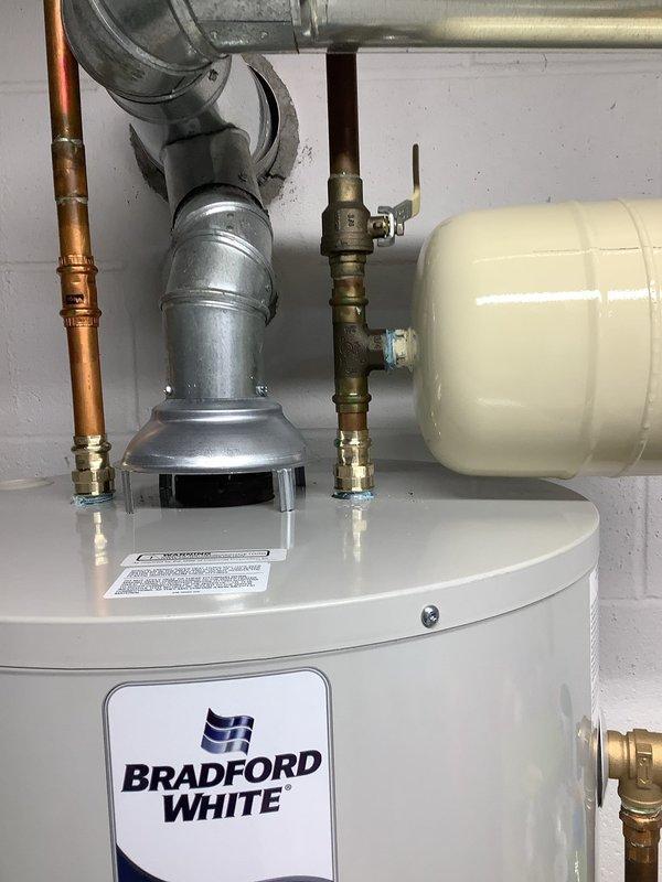 Successfully replaced water heater in basement location, requiring two technicians due to access limitations from chair lift. Installed new Bradford White unit with proper copper and galvanized vent connections, including expansion tank and necessary valve assembly. All components were properly mounted to concrete wall and tested for proper operation.