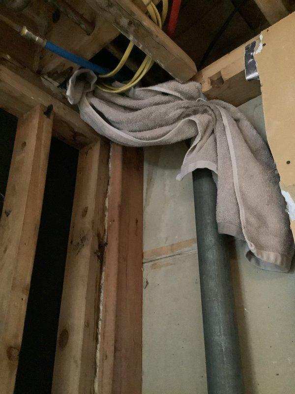 Performed leak investigation on a 1969-built home's plumbing system. Identified leakage point in vertical galvanized pipe running through wall framing. Addressed issue by temporarily securing with cloth while accessing the pipe through exposed framing area containing multiple utility lines (PEX water lines, electrical conduit).