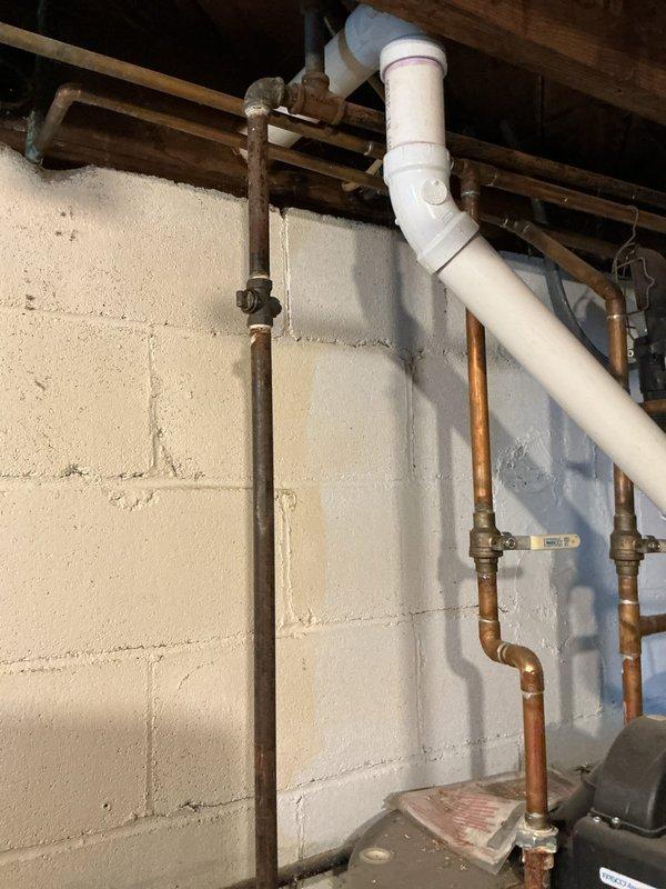 Performed diagnostic inspection on leaking Rheem tanked water heater. Confirmed water leakage from bottom of unit, indicating tank failure. Documented condition with photos showing installation configuration including PVC and copper piping connections, expansion tank, and basement drainage system. Recommended complete replacement of failed water heater.