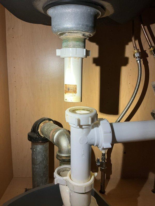 Responded to service call for kitchen sink drain issue in 60-year-old home. Upon inspection, found clogged P-trap with mineral buildup in the PVC assembly. Disassembled drain components, thoroughly cleaned the P-trap and drain pipes, removed accumulated debris and mineral deposits, then reassembled the plumbing system with proper connections. Verified proper drainage and absence of leaks after repair.