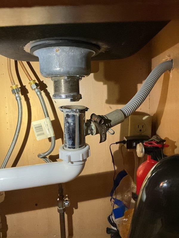 Responded to service call for kitchen sink drain issue in 60-year-old home. Upon inspection, found clogged P-trap with mineral buildup in the PVC assembly. Disassembled drain components, thoroughly cleaned the P-trap and drain pipes, removed accumulated debris and mineral deposits, then reassembled the plumbing system with proper connections. Verified proper drainage and absence of leaks after repair.
