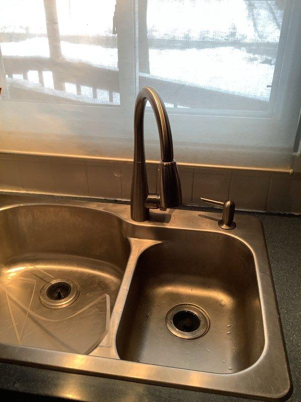 Replaced kitchen sink faucet that was not delivering hot water. Installation of new pull-down faucet with brushed nickel/bronze finish was completed successfully, resolving the hot water issue in the kitchen while maintaining functionality of the secondary fixture.