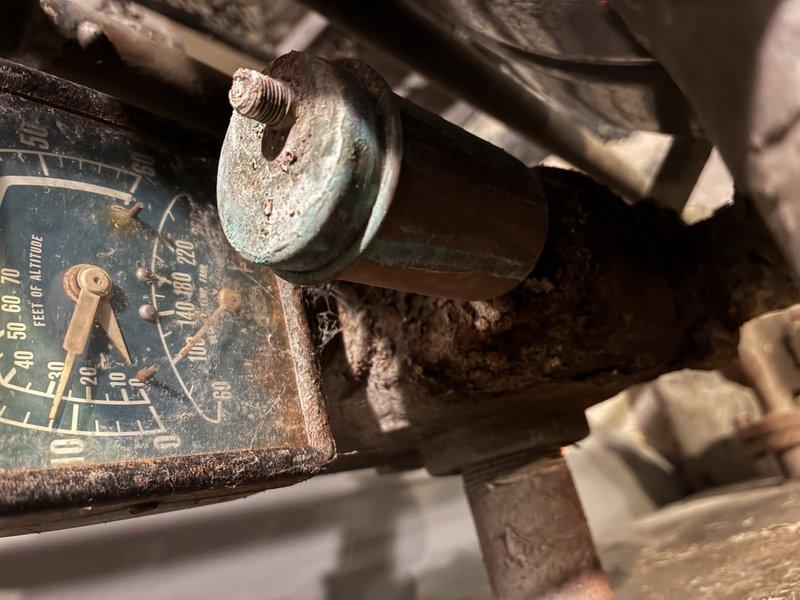 Performed diagnostic assessment on 50-year-old boiler system in response to customer request. Inspection revealed significant corrosion on pressure gauge with readings between 0-200 PSI, showing extensive wear and accumulated grime. Observed copper/brass components displaying greenish patina and deterioration at pipe joints, particularly at valve assembly. Recommended comprehensive maintenance service and potential component replacement due to age-related system degradation.