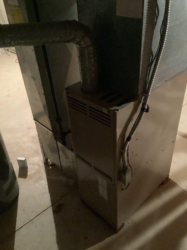 Completed installation of a new 80% efficient furnace and air conditioning system in customer's basement. Installed new galvanized ductwork with proper connections and seams, including insulated black return duct with 90-degree bend. System includes copper refrigerant lines connecting to the outdoor AC unit, with all necessary electrical connections properly secured.