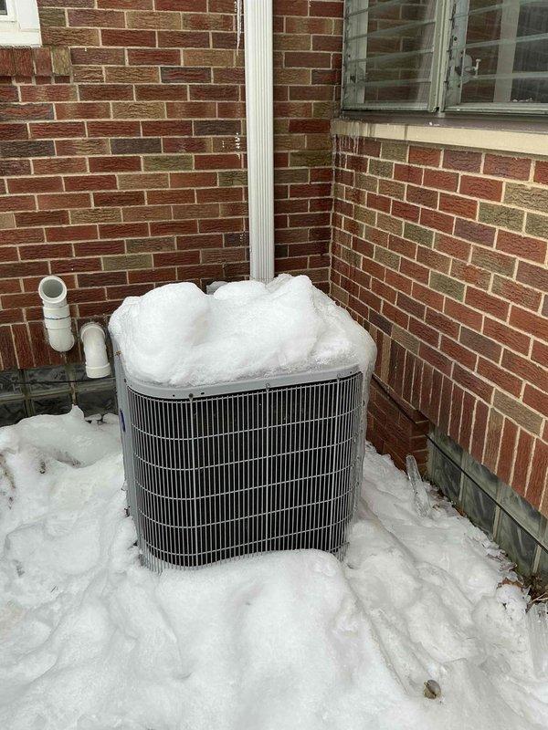 Conducted estimate for replacement of 16-year-old HVAC system. Current installation includes a Carrier humidifier mounted on the air handler with associated PVC drain lines and venting. Outdoor AC unit shows significant snow accumulation and exposure to elements, positioned against brick exterior wall with nearby drainage pipes.