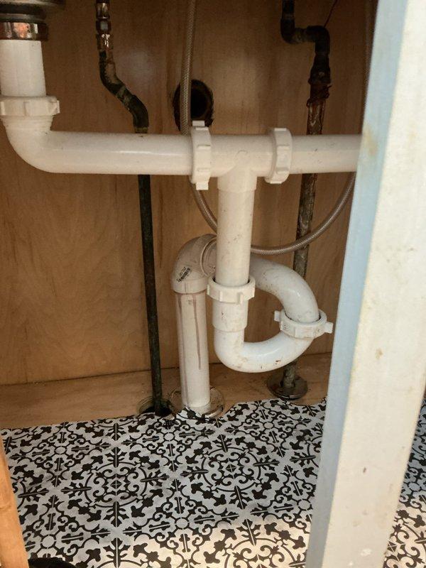 Responded to service call for clogged kitchen sink. Inspected under-sink PVC drain assembly and P-trap which showed signs of age. Located main drain connection in basement where copper fittings displayed mineral buildup and oxidation. Successfully cleared blockage and verified proper drainage function.