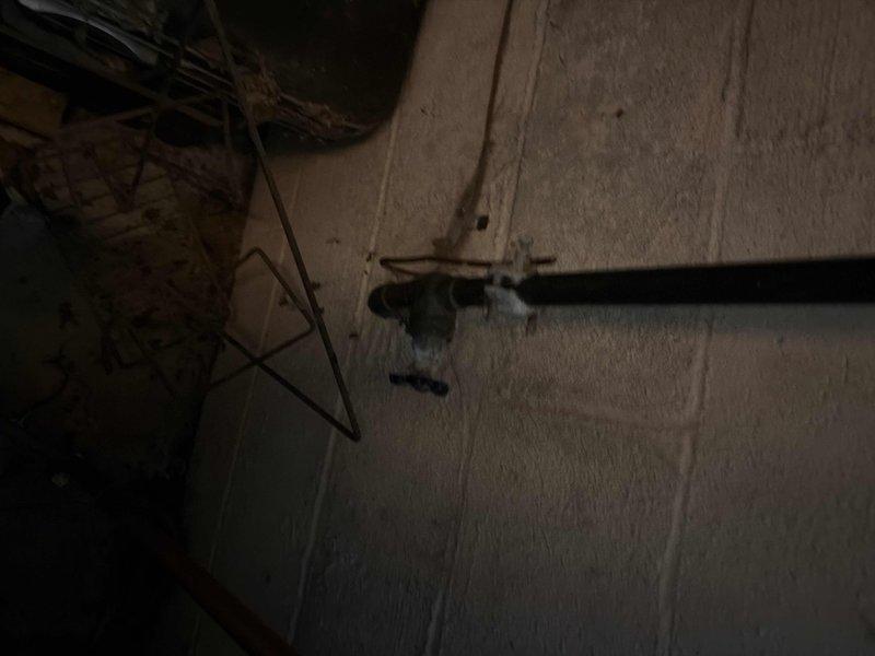 Completed main water valve replacement in customer's basement utility area. Accessed valve near cinder block wall where water line enters property, working around existing ductwork and pipe infrastructure. Service restored water functionality to the home after city water was shut off for the repair.