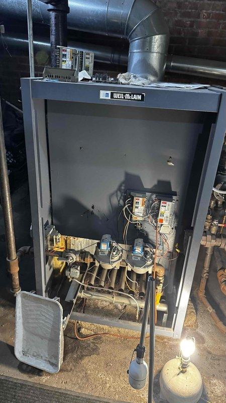 Inspected Weil-McLain LGB6 steam boiler system that customer reported as problematic. Visual examination revealed extensive corrosion and rust damage to the heat exchanger components, with active leaking observed. Documentation of the deterioration was captured for assessment purposes. System requires significant repairs or potential replacement of the heat exchanger assembly due to the advanced state of deterioration.