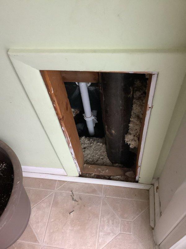 Responded to service call for bathtub drainage issue. Inspection revealed significant clogging in the drain line with mineral deposits and soap scum buildup visible in the basin. Accessed plumbing through wall panel to clear blockage in the main drain pipe, restoring proper water flow and drainage functionality.