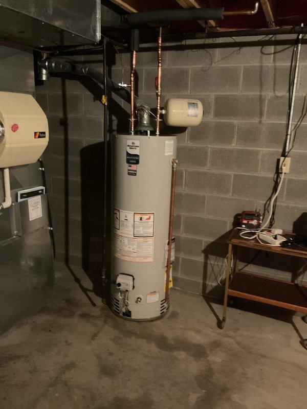 Successfully installed a new 40-gallon tall water heater in basement utility area, complete with ball valve, expansion tank, and 1/2x1/4 shut off valve. All components were properly connected with copper pipes and brass fittings to existing plumbing system.