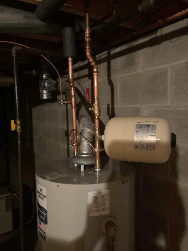Successfully installed a new 40-gallon tall water heater in basement utility area, complete with ball valve, expansion tank, and 1/2x1/4 shut off valve. All components were properly connected with copper pipes and brass fittings to existing plumbing system.