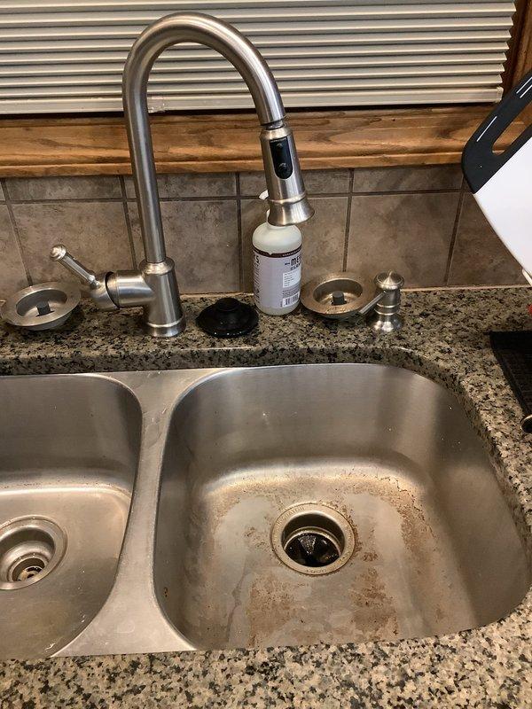 Cleared kitchen sink drain clog using professional equipment. Performed thorough cleaning of both basins in double stainless steel sink to remove mineral deposits and staining around drain areas. Sink and disposal now draining properly.