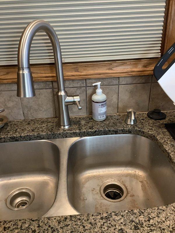 Cleared kitchen sink drain clog using professional equipment. Performed thorough cleaning of both basins in double stainless steel sink to remove mineral deposits and staining around drain areas. Sink and disposal now draining properly.