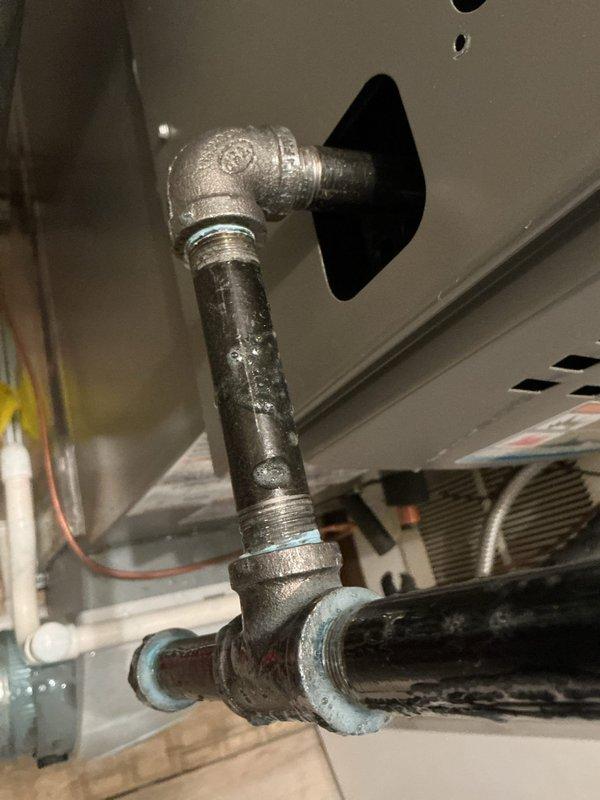 Responded to customer report of gas odor following recent furnace and gas line installation. Performed inspection of the mechanical room containing Rheem water heater and furnace system. Identified leak at threaded 90-degree elbow joint on newly installed gas piping. Customer had already contacted gas company who shut down furnace for safety. Noted that AC installation is still pending completion.