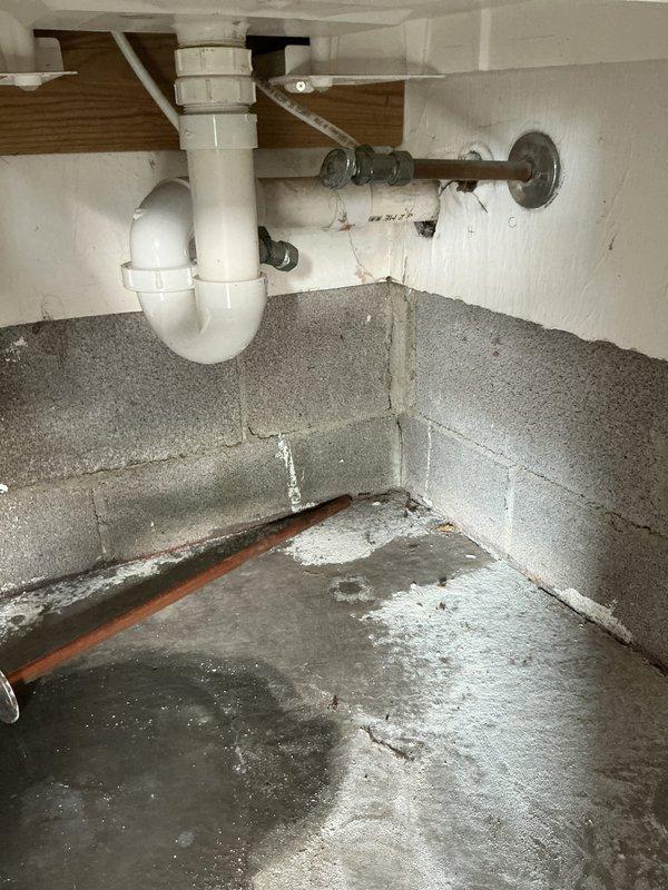 Responded to emergency call for broken pipe in garage with customer unable to locate shutoff valve. Located and repaired damaged PVC drainage pipe in basement/utility area, which showed signs of leakage evidenced by water staining on concrete floor. Installed new PVC fittings and ensured proper connection of P-trap to vertical drain pipe, restoring full functionality to the plumbing system.
