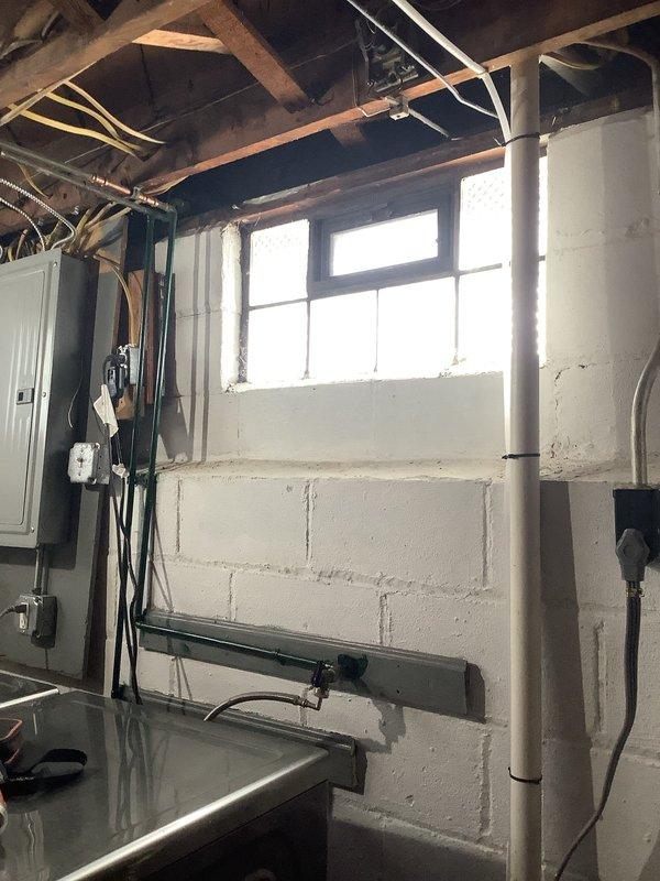 Responded to a no-power call at an 83-year-old residence with a broken outdoor electrical line. Inspection revealed significant corrosion at the service entrance, with visible rust damage where the conduit connects to the exterior wall. Replaced damaged service entrance cable and weatherhead, restored power to the main panel in basement, and verified all circuits functioning properly.