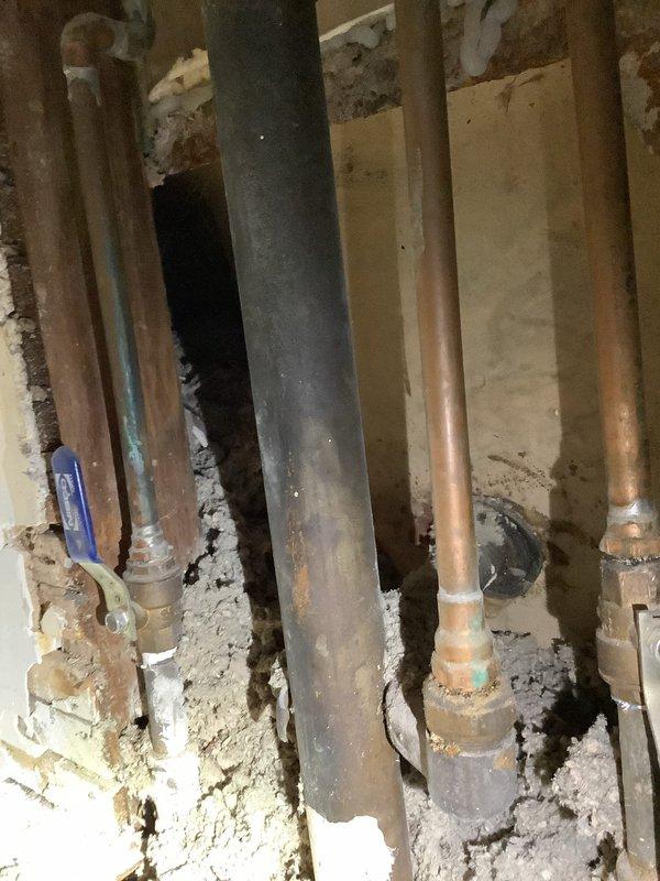 Responded to service call regarding leak in century-old tub spigot. Upon inspection, accessed wall cavity to examine plumbing system, revealing multiple copper supply lines with visible corrosion at connection points and a central waste pipe. Identified and repaired deteriorated fittings causing the leak, addressing associated water damage to surrounding wall structure.