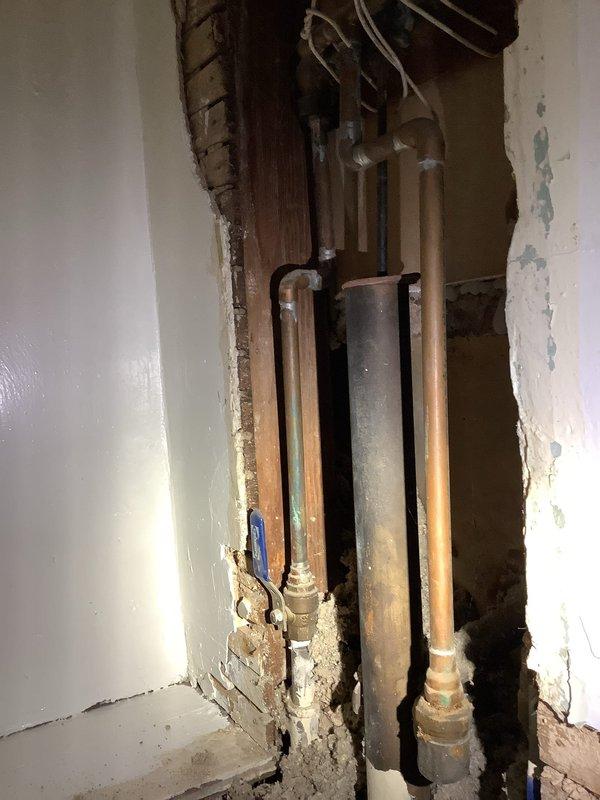 Responded to service call regarding leak in century-old tub spigot. Upon inspection, accessed wall cavity to examine plumbing system, revealing multiple copper supply lines with visible corrosion at connection points and a central waste pipe. Identified and repaired deteriorated fittings causing the leak, addressing associated water damage to surrounding wall structure.