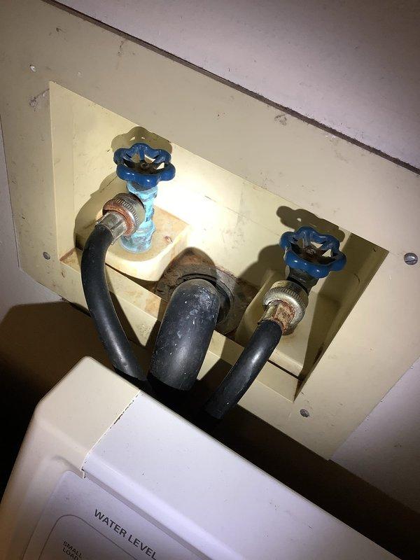Replaced leaking laundry room spigots with new blue manual shut-off valves. Installed new red valve handles with proper connections to the existing black supply hoses. Tested water flow and confirmed no leaks present after installation.