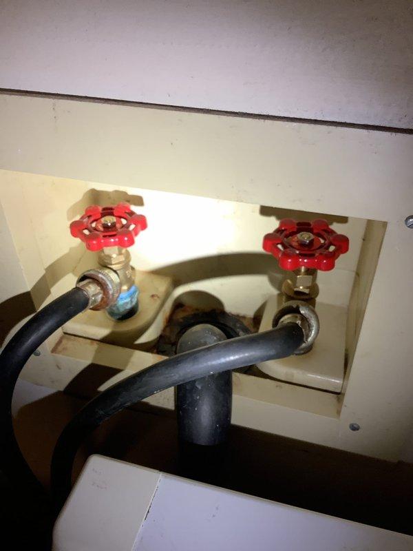 Replaced leaking laundry room spigots with new blue manual shut-off valves. Installed new red valve handles with proper connections to the existing black supply hoses. Tested water flow and confirmed no leaks present after installation.