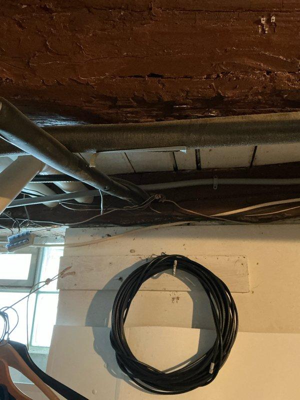 Conducted furnace replacement estimate for 13-year-old Armstrong system in older home with potential construction challenges. Inspection revealed exposed ductwork in utility area with electrical cables running alongside, as well as PVC plumbing infrastructure with purple markings at joints. Noted existing mechanical unit (possibly a humidifier) that would need to be integrated with any new installation.