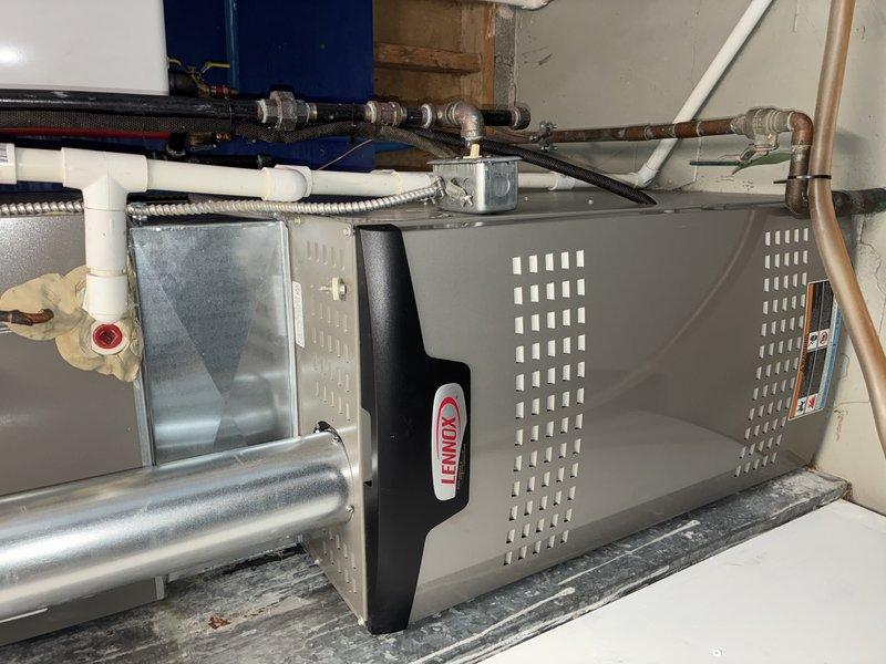 Performed routine MVP furnace maintenance service on Lennox heating system. Inspected Aprilaire Model #60 humidifier control, noting 0% humidity reading on digital display. Examined furnace connections including copper and PVC piping, ductwork, and associated plumbing components. Documented system condition with photos for service record.
