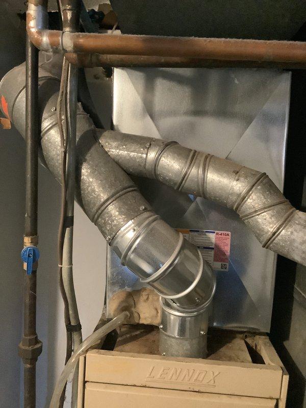 Conducted assessment of 44-year-old heating system requiring replacement. Inspected aging Lennox furnace with deteriorating copper lines, visible corrosion on pipe unions, and compromised ductwork connections. Photographed existing system configuration to develop appropriate replacement solution.