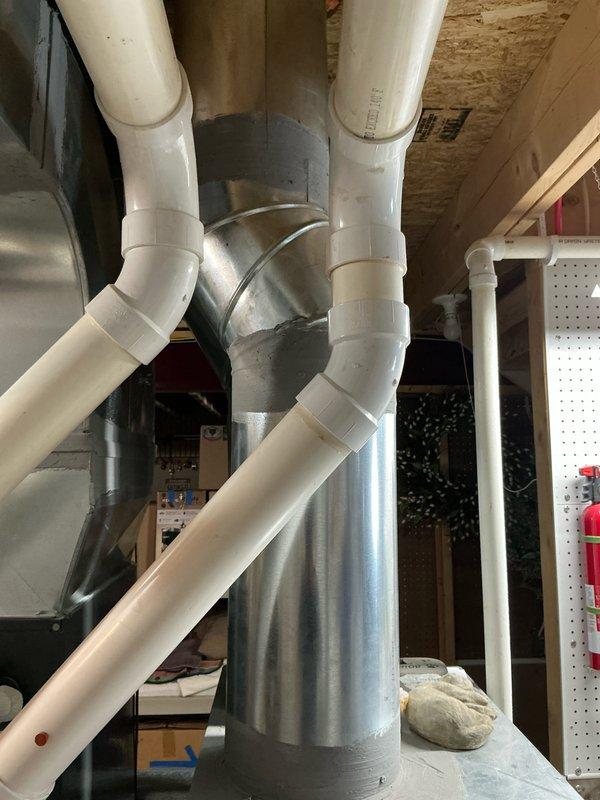 Conducted evaluation of 6-year-old Goodman furnace system that has previously undergone ignitor and blower motor replacements. System features PVC condensate drainage configuration running to floor drain and connects to galvanized trunk line with multiple PVC pipe connections. Provided replacement estimate for unit #1291 with documentation through comprehensive photos of the existing installation and ductwork configuration.