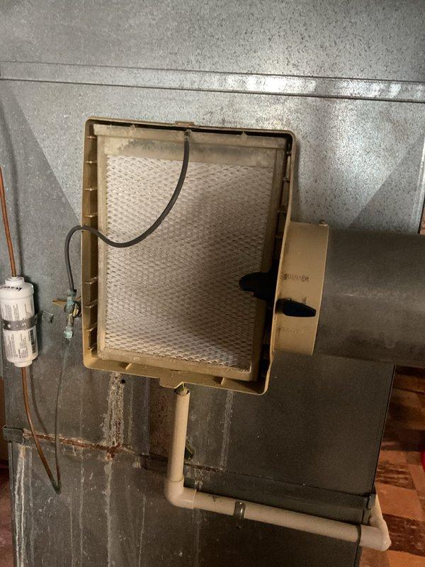 Performed scheduled MVP heating maintenance service, including inspection and evaluation of the humidifier system. Examined the evaporative pad which showed normal usage discoloration but remains functional. Used hex tool to access and check thermostat wiring connections (orange, red, green, white) to ensure proper system operation.