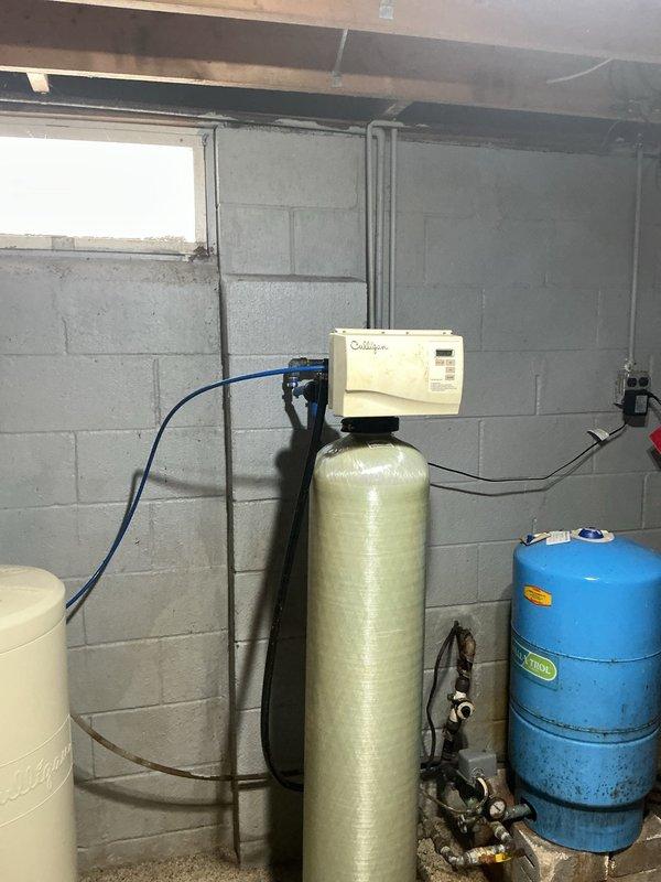 Replaced aging Culligan water softener system (10+ years old) that was actively leaking. Installed new water softener unit with associated plumbing connections, properly integrating it with the existing pressure tank and water treatment system in the basement utility area.
