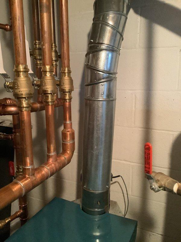 Completed warranty repair on boiler installation that had previously failed inspection due to non-compliant exhaust ducting. Corrected the exhaust duct connection to ensure proper 2" lap at the crimp area, which previously had 1.5" exposure. Verified all copper supply lines, brass valves, and galvanized flue connections were properly secured and functioning according to manufacturer specifications.