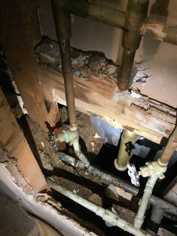 Responded to a no-water service call at a multi-unit building with 3 hot water heaters and a boiler. Inspection revealed significant water damage to structural wood elements with visible deterioration and mold formation. Documented extensive damage to the plumbing system including corroded copper and PVC pipes. Also inspected the pressure regulation system which showed signs of leakage at the regulator/valve assembly and possible issues with the flow control mechanism.
