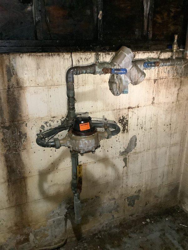 Responded to no-water service call at multi-unit building with 3 hot water tanks and boiler system. Inspection revealed significant water damage and fire/smoke damage to the basement utility area, with compromised plumbing fixtures including a main valve with an orange warning label. Identified and repaired faulty pressure regulator valve that was preventing water flow to the building.