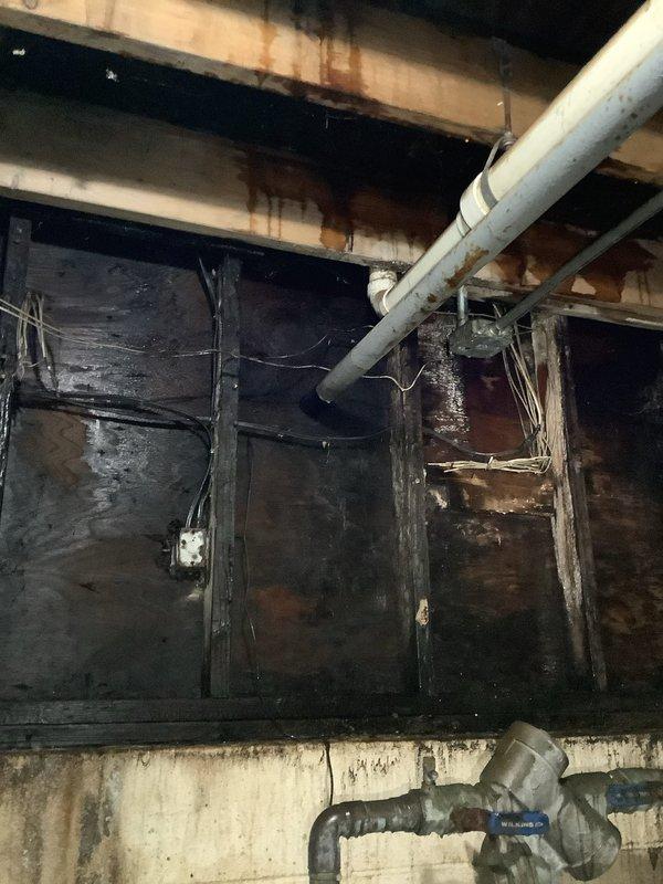 Responded to no-water service call at multi-unit building with 3 hot water tanks and boiler system. Inspection revealed significant water damage and fire/smoke damage to the basement utility area, with compromised plumbing fixtures including a main valve with an orange warning label. Identified and repaired faulty pressure regulator valve that was preventing water flow to the building.