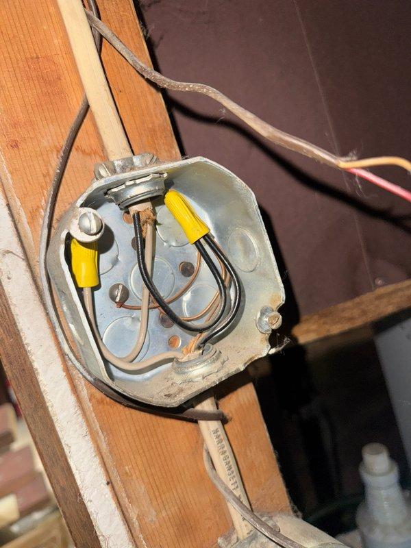 Performed inspection of electrical junction box mounted on wooden framing, identified exposed conductors with yellow wire nuts and improper connections. Resolved safety hazard by properly securing all connections, verifying proper grounding, and ensuring code compliance of the installation.