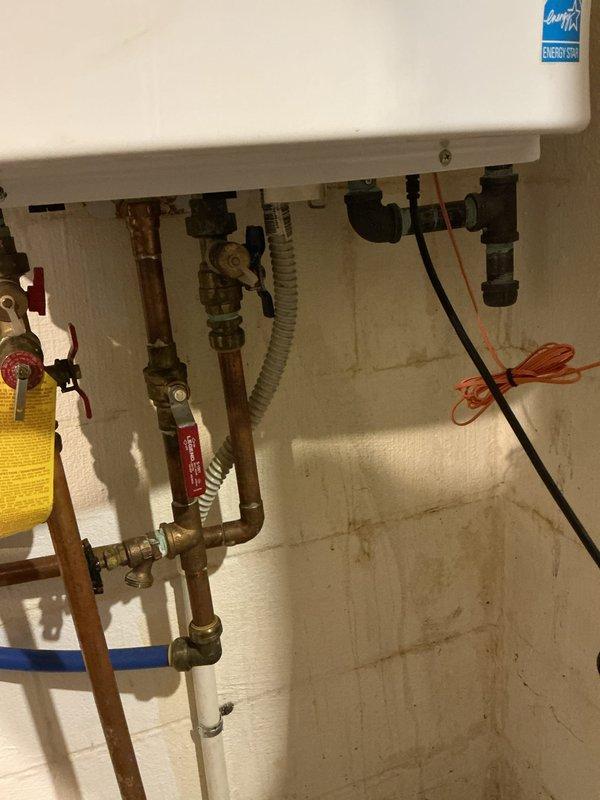 Performed descaling service on tankless water heater to remove mineral buildup and restore optimal performance. Inspected copper and brass pipe infrastructure beneath unit, which showed signs of age and tarnishing. Examined leaking humidifier as requested, noting temperature settings on thermostat (80°) and evaluating connection issues.