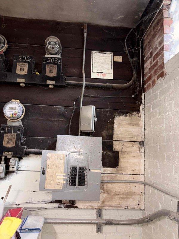 Performed inspection and assessment of aging 20-year-old commercial steam boiler system requiring replacement. Evaluated electrical service panel and existing boiler installation against brick wall in utility area. Documented current configuration with photographs to develop comprehensive replacement proposal.