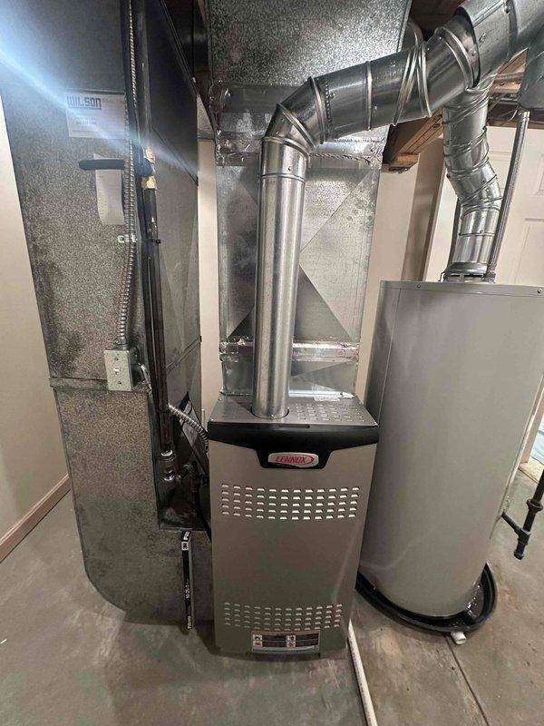 Completed installation of an 80% efficient Lennox furnace along with hot water tank as part of second job phase. Installation included proper ductwork connections sealed with metal tape, PVC condensate drain line routing, and all necessary gas/electrical hookups in utility area. System was mounted securely against wall with all components properly connected and tested.