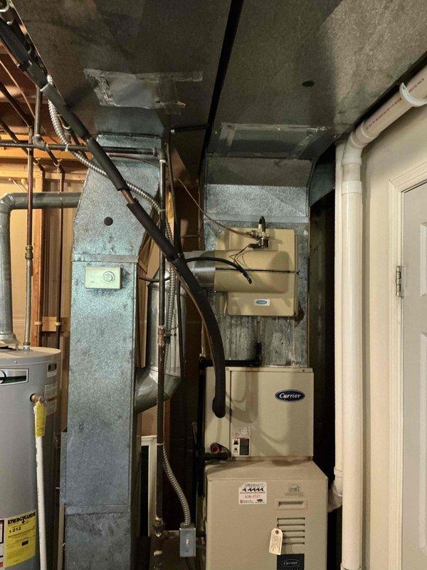 Conducted inspection of 27-year-old Carrier HVAC system for potential replacement. Unit is showing significant age with weatherproofing concerns evident by protective covering on outdoor component. Evaluated existing ductwork configuration and utility room layout to determine appropriate replacement options for both furnace and possible AC upgrade.