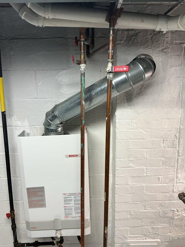 Successfully replaced existing water heater with new Navien NPE-240-A2 tankless unit, installing it 18 inches higher than previous location with proper venting to exterior. Completed comprehensive plumbing improvements including removal of main water line filter, replacement of corroded valves, and reconfiguration of piping to improve walkway clearance near furnace. Added strategic shut-off valves and rebuilt feed lines for improved functionality and access.