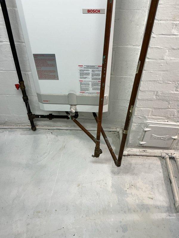 Successfully replaced existing water heater with new Navien NPE-240-A2 tankless unit, installing it 18 inches higher than previous location with proper venting to exterior. Completed comprehensive plumbing improvements including removal of main water line filter, replacement of corroded valves, and reconfiguration of piping to improve walkway clearance near furnace. Added strategic shut-off valves and rebuilt feed lines for improved functionality and access.