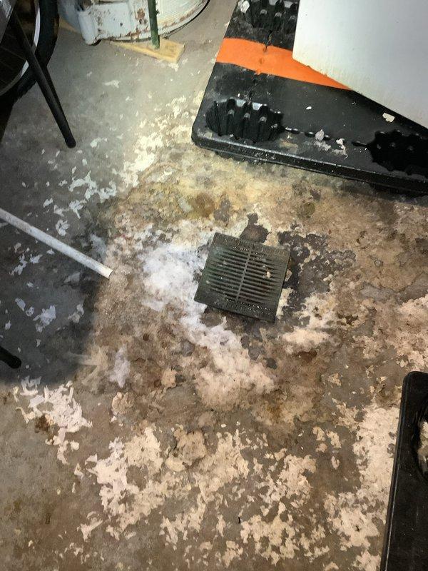 Conducted comprehensive camera inspection of floor drain system in basement utility area. Identified significant debris accumulation around drain grate and documented presence of white powdery material (possible insulation) scattered across concrete floor. Visual inspection also revealed deterioration of drainage components and potential ventilation system issues associated with the nearby HVAC equipment.