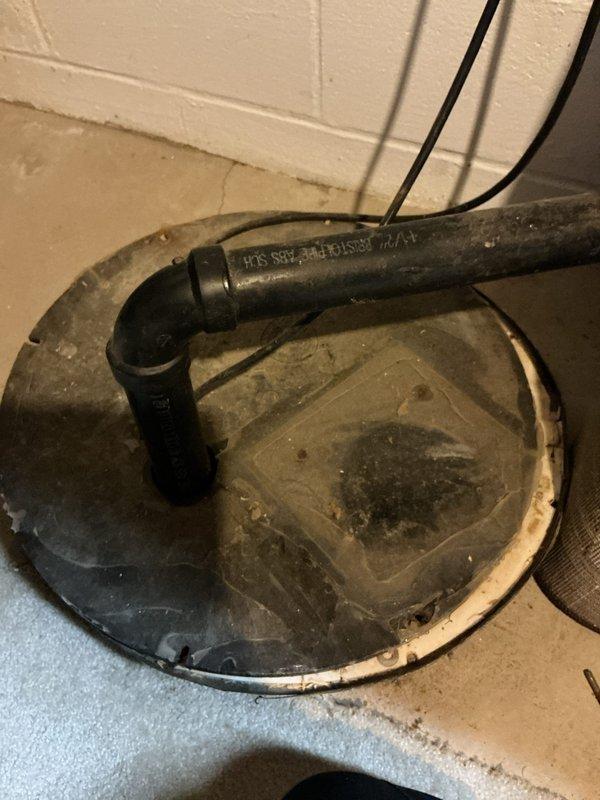 Responded to service call for sump pump issues in basement. Inspected system components including the black PVC drainage pipe, pump cover, and electrical connections mounted on concrete block wall. Identified and resolved drainage system problems to restore proper sump pump functionality.