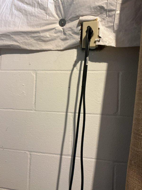 Responded to service call for sump pump issues in basement. Inspected system components including the black PVC drainage pipe, pump cover, and electrical connections mounted on concrete block wall. Identified and resolved drainage system problems to restore proper sump pump functionality.