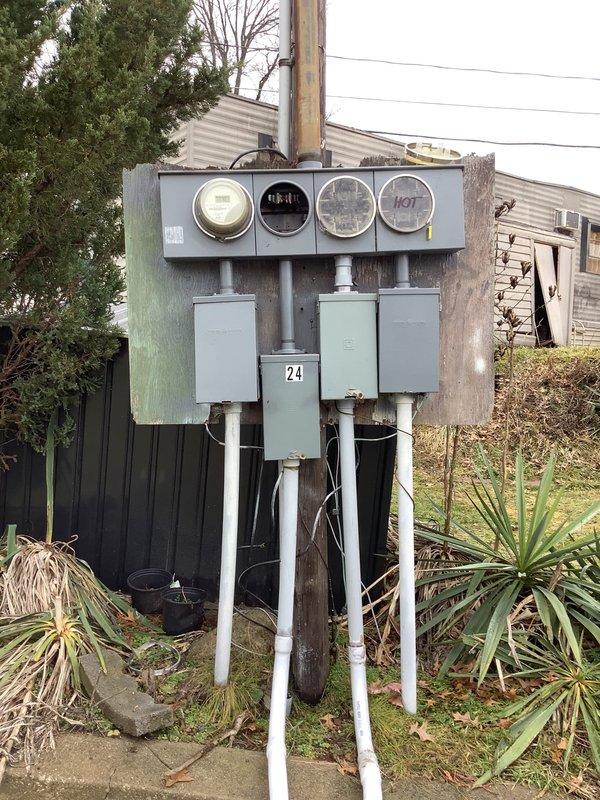 Conducted inspection of existing meter bank installation on utility pole, which includes four-meter interfaces (one labeled "HOT") and three electrical boxes connected by conduit. Assessed condition of meter base for potential upgrade as requested by customer and documented current installation with photographs for estimate preparation.