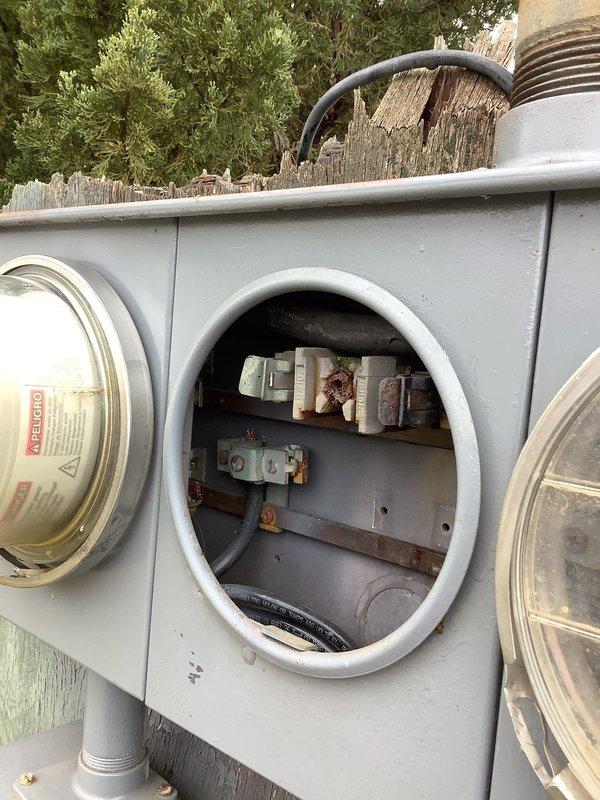 Conducted inspection of existing meter bank installation on utility pole, which includes four-meter interfaces (one labeled "HOT") and three electrical boxes connected by conduit. Assessed condition of meter base for potential upgrade as requested by customer and documented current installation with photographs for estimate preparation.